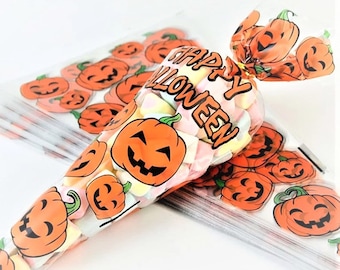 May include: Transparent cellophane bags filled with colourful marshmallows. The bags are decorated with orange jack-o'-lanterns and the words "Happy Halloween" in white. Several bags are stacked together, perfect for Halloween treats.