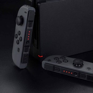 May include: Two gray Nintendo Switch Joy-Con controllers with red indicator lights. The controllers are shown attached to a black Nintendo Switch console.