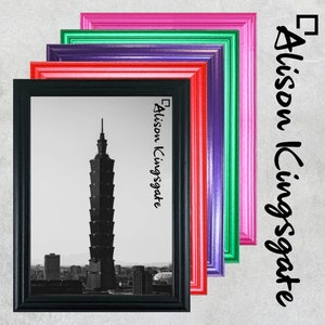 Puede incluir: Cinco marcos de fotos de diferentes colores, apilados uno encima del otro. Los marcos son rosa, verde, morado, rojo y negro. El marco negro tiene una foto en blanco y negro de un edificio alto en una ciudad. El texto "Alison Kingsgate" está escrito en el marco.