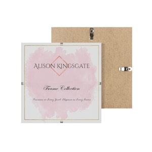 May include: A white picture frame with a gold border and the text "ALISON KINGSGATE Frame Collection" on a pink watercolour background. The frame is in front of a brown backing board with hanging hardware.