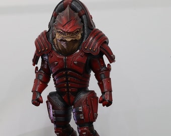 May include: A red and black action figure of a fictional alien warrior wearing armor. The figure has a detailed sculpt and paint job.