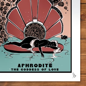 May include: Aphrodite, the Goddess of Love, is depicted in a black silhouette lying on a red shell in a teal blue water scene. The background features a red and white fan-shaped design with a black and white mandala in the centre.