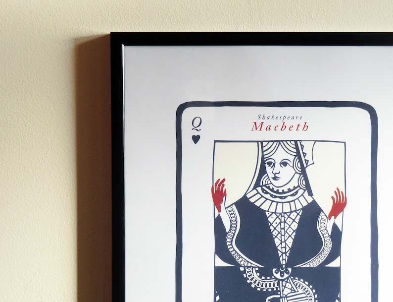 May include: A black framed print of a Queen of Hearts playing card with the text "Shakespeare Macbeth" at the top. The Queen is depicted in a blue and white dress with red hands.