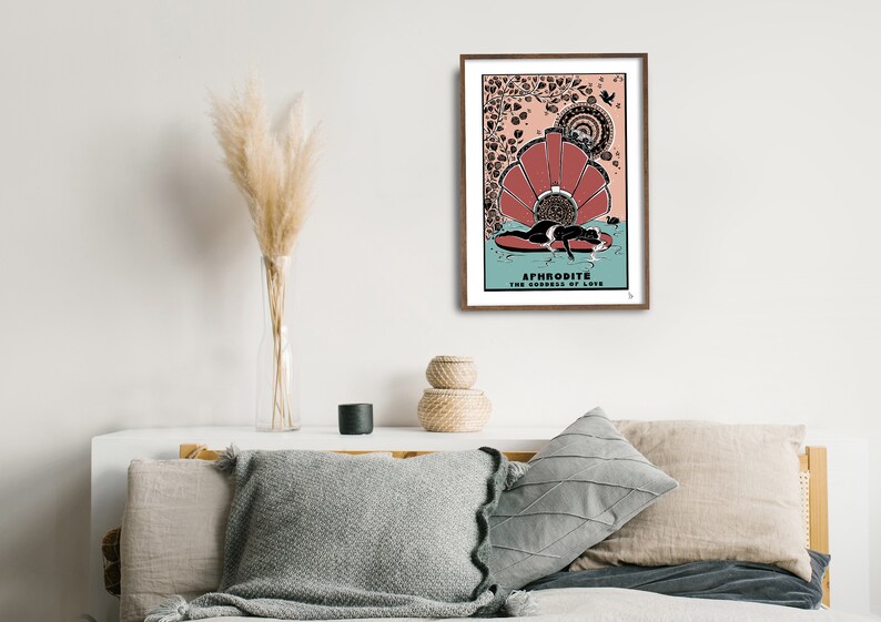 May include: A framed print of a goddess with a crown of flowers, lying on a seashell. The print is in a brown frame and has the text "APHRODITE THE GODDESS OF LOVE" at the bottom.