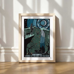 May include: A framed print of a stylized illustration of Artemis, the Greek goddess of the hunt and the moon. The image features Artemis standing on a cliff with a dog and a waterfall in the background. The print is in a wooden frame and has a white background.