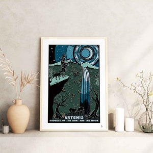 May include: A framed print of a goddess with a bow and arrow, standing in a forest with a waterfall. The print is titled "Artemis, Goddess of the Hunt and the Moon".