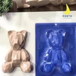 May include: A silicone mold for making a geometric bear-shaped cake or chocolate. The mold is blue and has a hanging loop. The finished product is a light brown geometric bear.