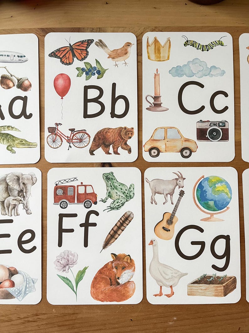 May include: A set of alphabet flash cards featuring colorful illustrations and the letter 'A' through 'G' in uppercase and lowercase. The cards include images of an airplane, butterfly, bear, car, elephant, fire truck, goat, goose, and more.