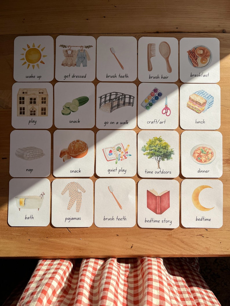 May include: A set of 20 illustrated cards depicting daily activities for children. The cards feature simple illustrations of activities like waking up, getting dressed, brushing teeth, playing, snacking, going on a walk, crafting, having lunch, napping, quiet play, spending time outdoors, having dinner, taking a bath, putting on pajamas, reading a bedtime story, and going to bed.