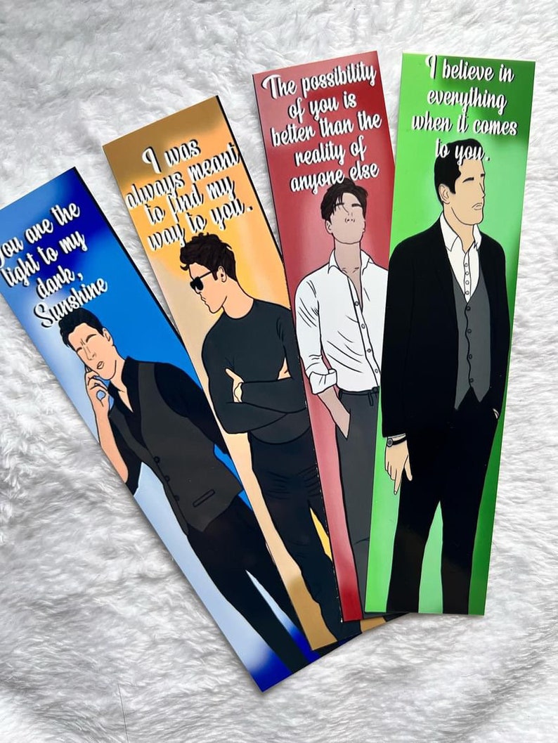 May include: Four bookmarks with illustrations of men and romantic quotes. The bookmarks have a gradient background of blue, gold, and red. The quotes include "You are the light to my dark, Sunshine" and "I was always meant to find my way to you."