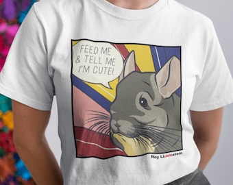 May include: White t-shirt featuring a pop art style graphic of a chinchilla with the text "FEED ME & TELL ME I'M CUTE!". The graphic is in a comic book style with bold lines and bright colors. The artist's name, Roy Lichinstein, is at the bottom.