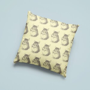 May include: Square throw pillow with a repeating pattern of vintage-style chinchilla illustrations in shades of gray on a pale yellow background. The pillow is a decorative item, likely for a living room or bedroom.