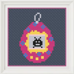 Può includere: Opera d'arte a punto croce di un dispositivo di gioco portatile retrò. Il design rosa, giallo e blu presenta un personaggio alieno pixelato su uno sfondo grigio. L'opera è incorniciata in una cornice quadrata bianca.