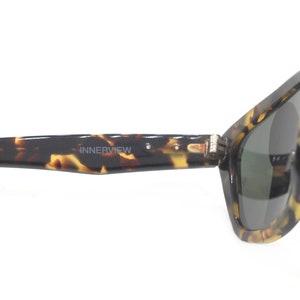 May include: Tortoise shell sunglasses with dark green lenses. The sunglasses have the word "INNERVIEW" printed on the frame.
