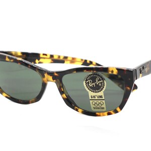 May include: Tortoise shell Ray-Ban sunglasses with green lenses and a gold sticker that says "G-15 Lens" and has the Olympic rings logo.