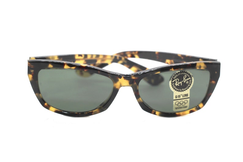May include: Tortoise shell Ray-Ban sunglasses with green lenses and a G-15 lens label. The sunglasses have a classic cat-eye shape.