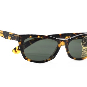 May include: Tortoise shell sunglasses with green lenses and a Ray-Ban label on the side.