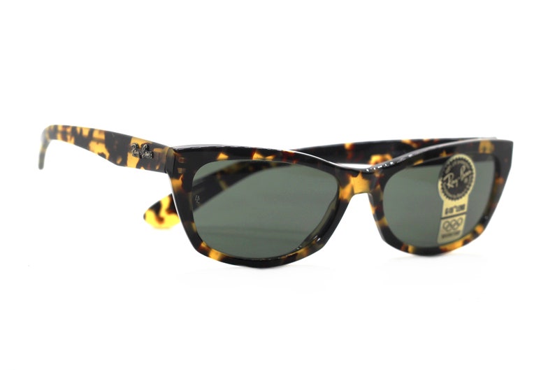 May include: Tortoise shell sunglasses with green lenses and a Ray-Ban label on the side.