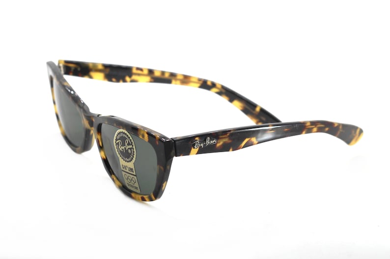 May include: Tortoise shell Ray-Ban sunglasses with green lenses. The sunglasses have a classic, rectangular shape and a thin frame.