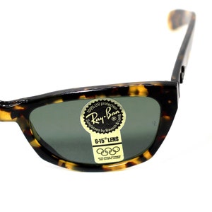 May include: Tortoise shell Ray-Ban sunglasses with green lenses. The sunglasses have a sticker on the right lens that says "100% UV protection Ray-Ban Sunglasses by Bausch & Lomb G-15 LENS".