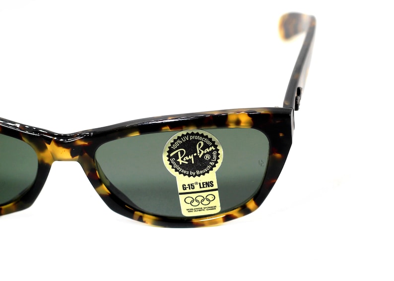 May include: Tortoise shell Ray-Ban sunglasses with green lenses. The sunglasses have a sticker on the right lens that says "100% UV protection Ray-Ban Sunglasses by Bausch & Lomb G-15 LENS".