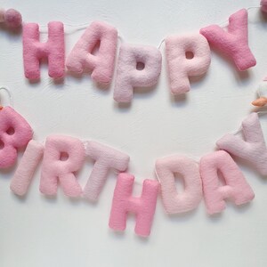 May include: Pink felt banner with the words "Happy Birthday" strung together with white thread.