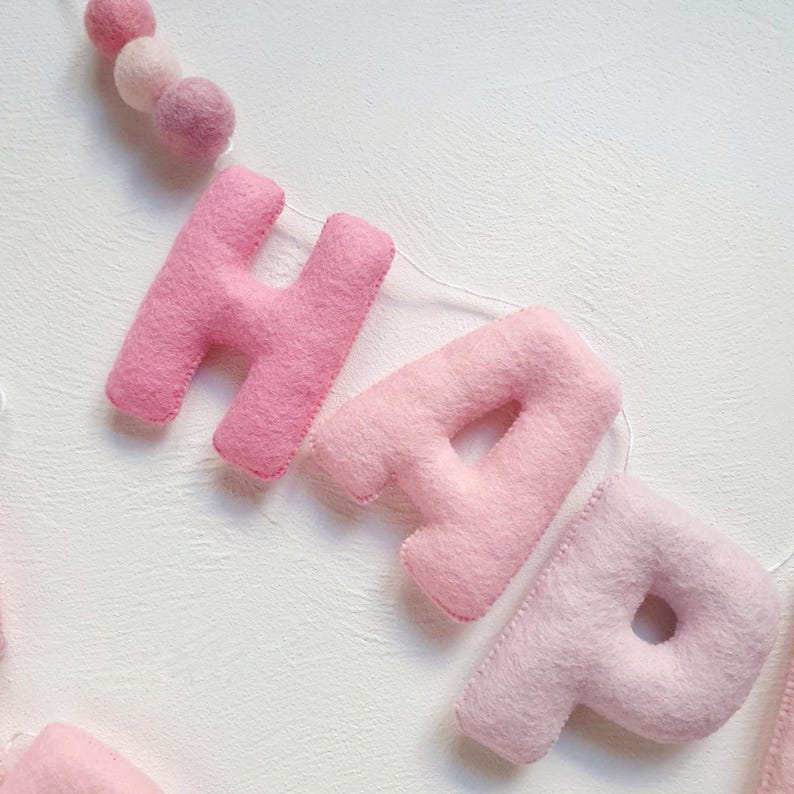 May include: Pink felt letter banner spelling out "Happy" with a string of pink felt balls.
