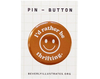Könnte beinhalten: Ein brauner Knopf mit einem weißen Smiley und dem Text "I'd rather be thrifting." Der Knopf befindet sich auf einem weißen Hintergrund mit einem Gittermuster.