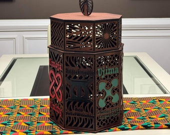May include: A wooden box with intricate laser cut designs and the seven principles of Kwanzaa inscribed on each side. The box is brown with red, green, and black accents. The principles are Umoja (Unity), Kujichagulia (Self-determination), Ujima (Collective Work and Responsibility), Ujamaa (Cooperative Economics), Nia (Purpose), Kuumba (Creativity), and Imani (Faith).