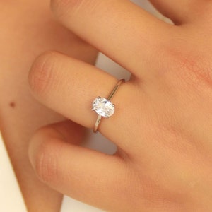 Featuring dainty oval cut colourless cubic zirconia diamond set in thin high quality sterling silver band. Perfect as an engagement ring backup, this diamond simulant ring offers a brilliant shine that catches the light beautifully.