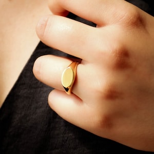 Featuring medium sized plain oval signet ring made with yellow gold plating.