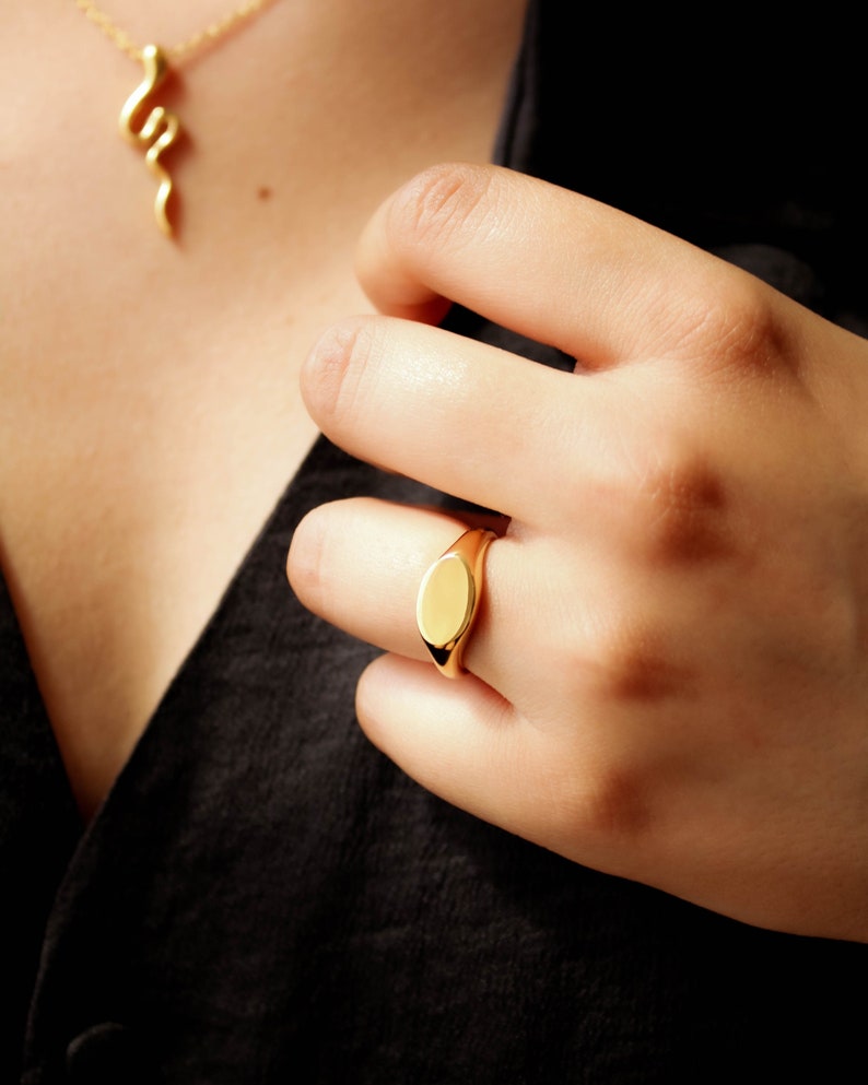 Featuring medium sized plain oval signet ring made with yellow gold plating.