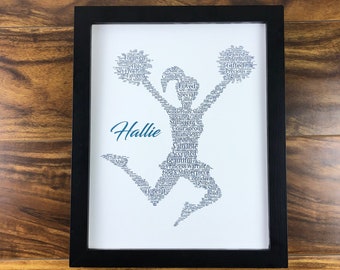 May include: A framed print with a word cloud in the shape of a cheerleader. The word cloud is made up of positive words like "loved", "gifted", "precious", "courageous", and "valuable". The name "Hallie" is written in blue at the bottom of the print.