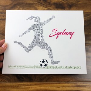 word art with words in the shape of a female soccer player and colored black. Ground below is green. Hot pink name printed beside player. The words in the print remind her of identity in Christ - God’s masterpiece, valuable, loved, forgiven, etc