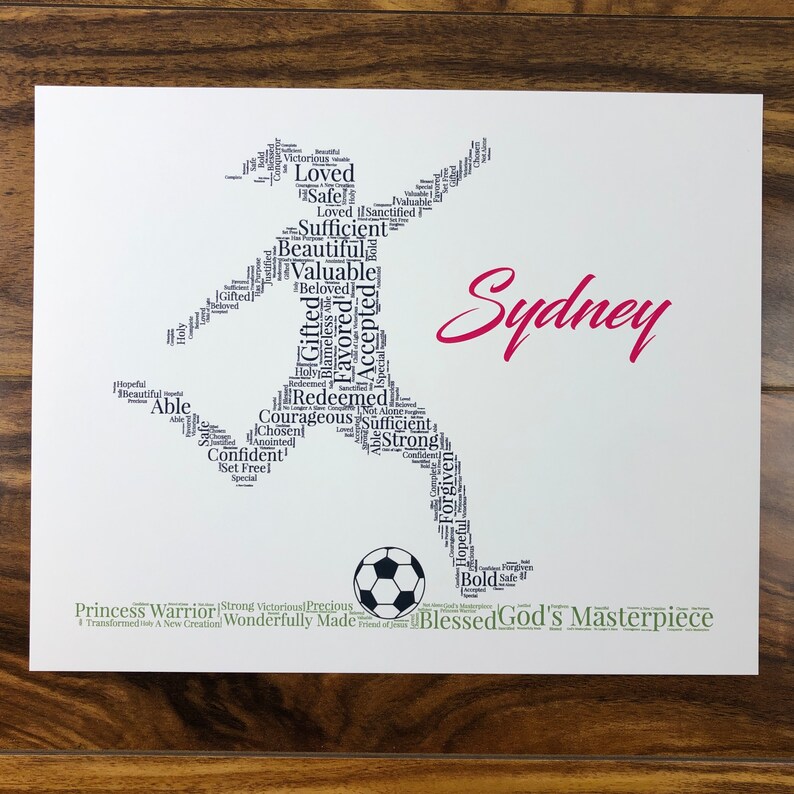 word art with words in the shape of a female soccer player and colored black. Ground below is green. Hot pink name printed beside player. The words in the print remind her of identity in Christ - God’s masterpiece, valuable, loved, forgiven, etc