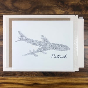 Word art with words in the shape of an airplane in gray color. Black name printed below airplane. The words in the print remind him of identity in Christ - God’s handiwork, valuable, loved, forgiven, etc.