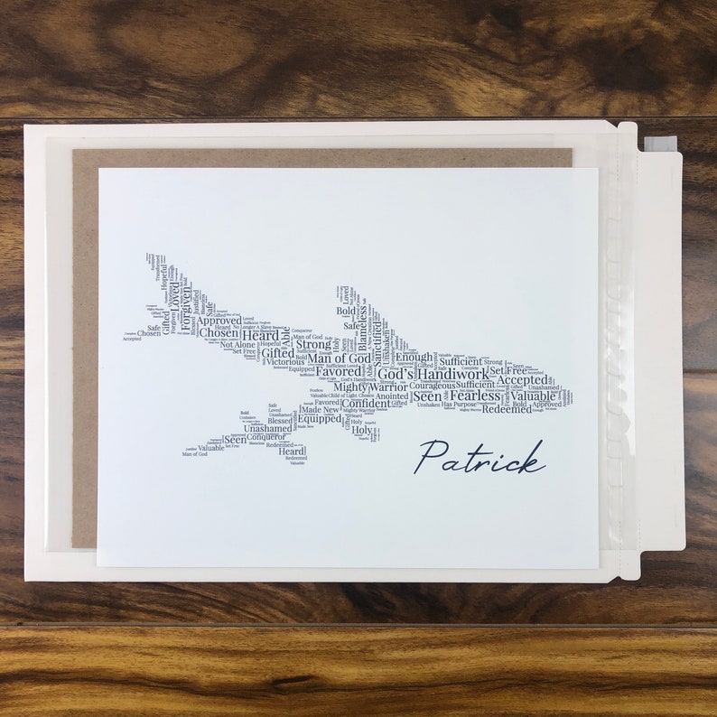 Word art with words in the shape of an airplane in gray color. Black name printed below airplane. The words in the print remind him of identity in Christ - God’s handiwork, valuable, loved, forgiven, etc.