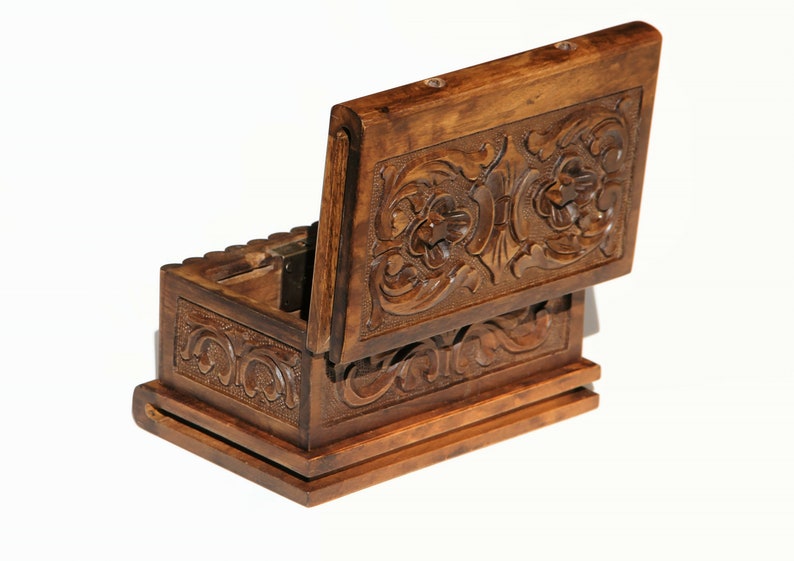 May include: A wooden box with intricate carvings on the lid and sides. The lid is open, revealing the empty interior of the box.