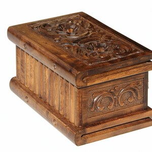 May include: A wooden box with intricate carvings on the top and sides. The box is made of dark brown wood and has a hinged lid.