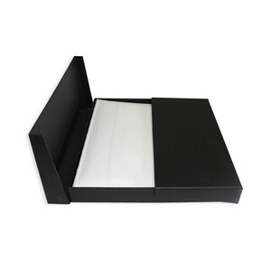 May include: A black box with a white interior, the lid is open and the interior is visible.