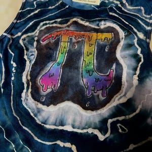 May include: A tie-dye tank top with a rainbow-colored Pi symbol graphic. The Pi symbol has a dripping effect, with colors transitioning from red to purple. The tank top has a blue and white tie-dye pattern and a tag that reads "Moon Pie Apparel."