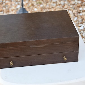 May include: A dark brown wooden jewellery box with two drawers and brass knobs.