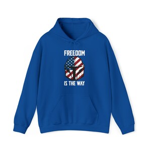 May include: A royal blue hoodie with a front graphic featuring a helmet design incorporating the American flag. The text "FREEDOM IS THE WAY" is printed above and below the helmet design. The hoodie has a drawstring hood and a front pocket.