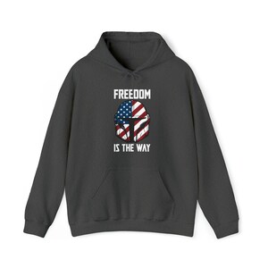 May include: Dark gray hoodie with a front graphic featuring a helmet design incorporating the American flag. The text "FREEDOM IS THE WAY" is printed above and below the helmet design in white block letters. The hoodie has a drawstring hood and a front pocket.