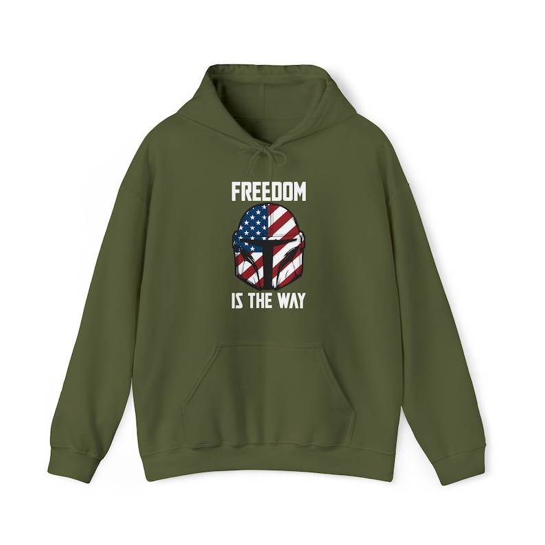 May include: Olive green hoodie with a front graphic featuring a helmet design incorporating the American flag and the text "FREEDOM IS THE WAY" in white. The hoodie has a drawstring hood and a front pocket.