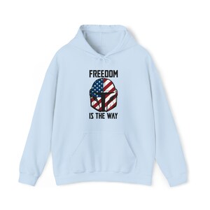 May include: Light blue hoodie with a front graphic featuring a helmet design incorporating the American flag. The text "FREEDOM IS THE WAY" is printed above and below the helmet design. The hoodie has a drawstring hood and a front pocket.