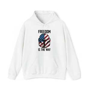 May include: White hooded sweatshirt with a front pocket and drawstring. The design features a helmet graphic with the American flag and the text "FREEDOM IS THE WAY" in black.