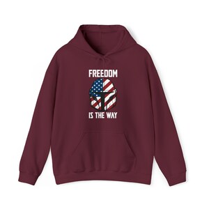 May include: Burgundy hoodie with a front graphic featuring a helmet design incorporating the American flag and the text "FREEDOM IS THE WAY" in white. The hoodie has a drawstring hood and a front pocket.