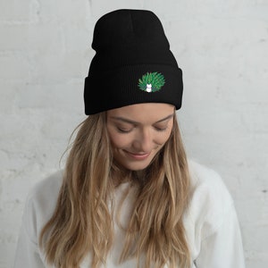 Pode incluir: Boné preto com um design bordado em verde e branco de um gato com uma coroa de folhas na cabeça.