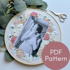 May include: A white embroidery hoop with a floral design in shades of pink and white. A black and white photo is centered in the hoop. The text "PDF Pattern" is written in white on a pink circle.